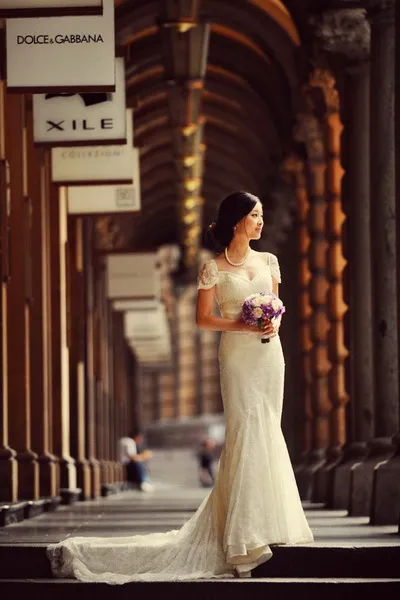 the bride wears a classic lace wedding dress and stands in the Sydney store corridor