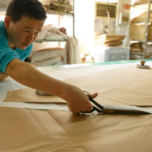 Master craftsman precisely cutting a bridal gown pattern in our workshop.