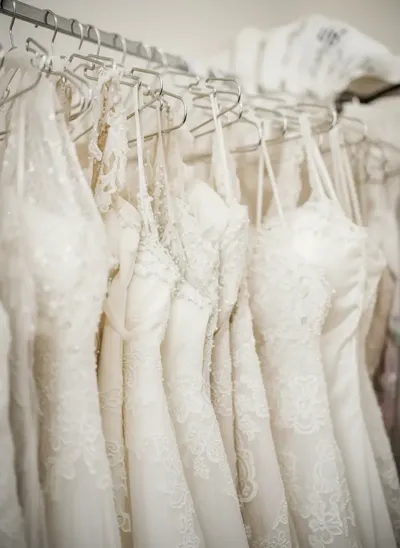 Dettaglio del corpetto di un abito da sposa riccamente decorato con paillettes, appeso a un attaccapanni, che mette in mostra la sua trama intricata.