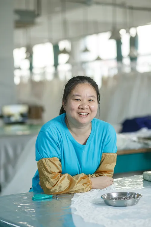 Un membro sorridente dello staff di una fabbrica lavora in un laboratorio di abiti da sposa