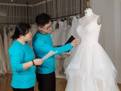 Design team discussing wedding dress sketches and fabrics at AiDo Factory.