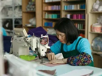 Skilled seamstress sewing intricate details on a wedding gown.