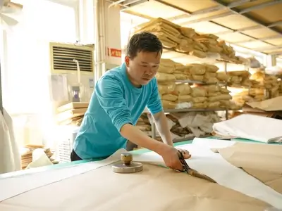 Expert cutter working on fabric patterns for custom wedding dresses.